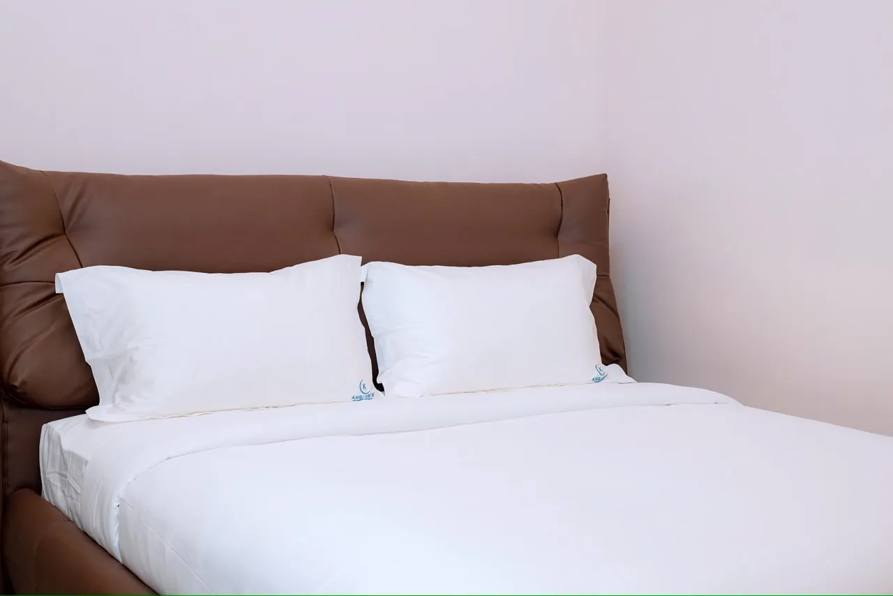White pillows and bedding against a brown upholstered headboard