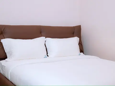 White pillows and bedding against a brown upholstered headboard