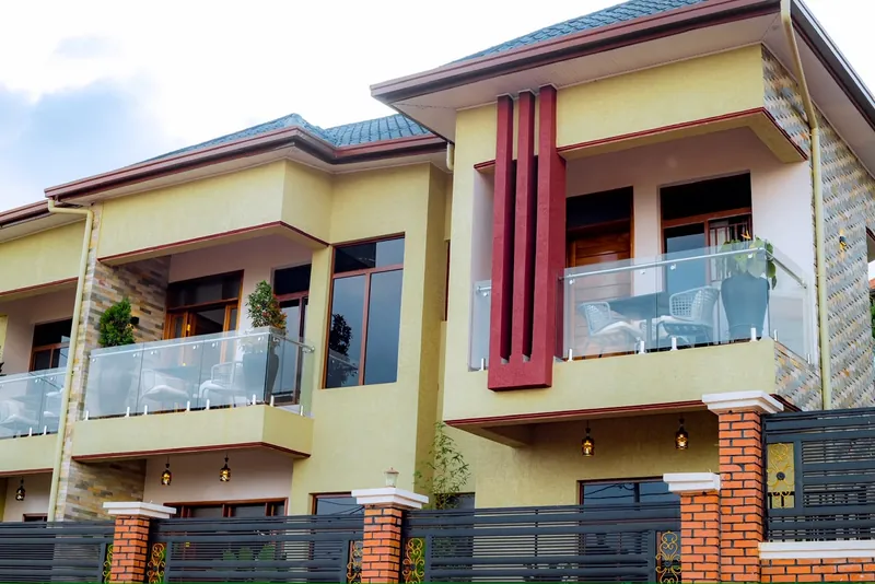 Yellow exterior with glass balconies, burgundy columns and a dark metal gate