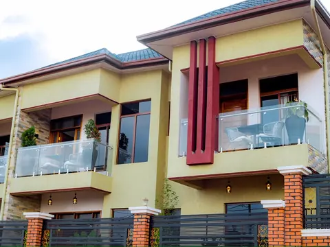 Yellow exterior with glass balconies, burgundy columns and a dark metal gate