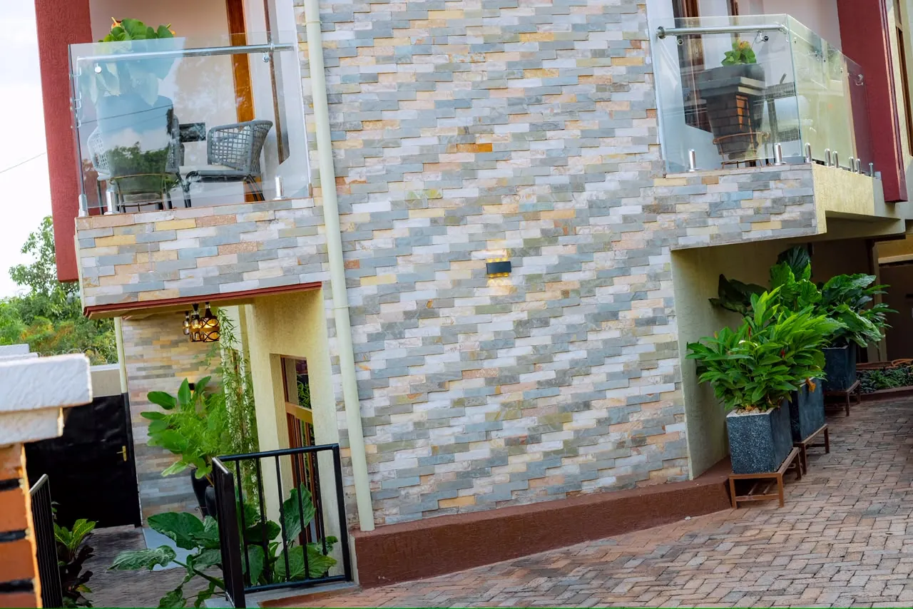 Tiled exterior wall between two glass balconies, above a paved walkway