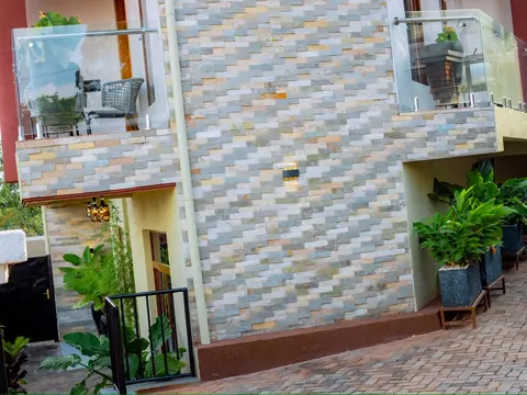 Tiled exterior wall between two glass balconies, above a paved walkway
