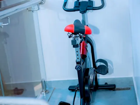 Indoor exercise bike with a red and black seat and black handlebars