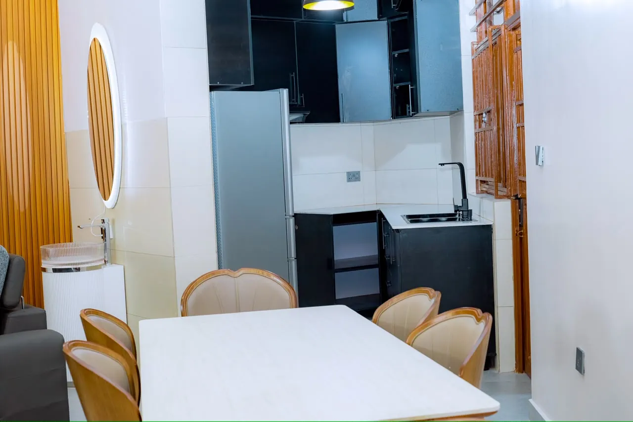 White dining table and upholstered chairs beside the kitchen cabinets
