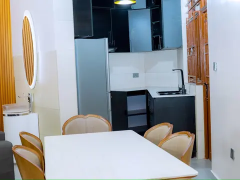 White dining table and upholstered chairs beside the kitchen cabinets