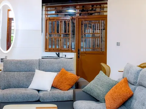 Gray sectional seating with accent cushions, coffee tables and a dining area behind