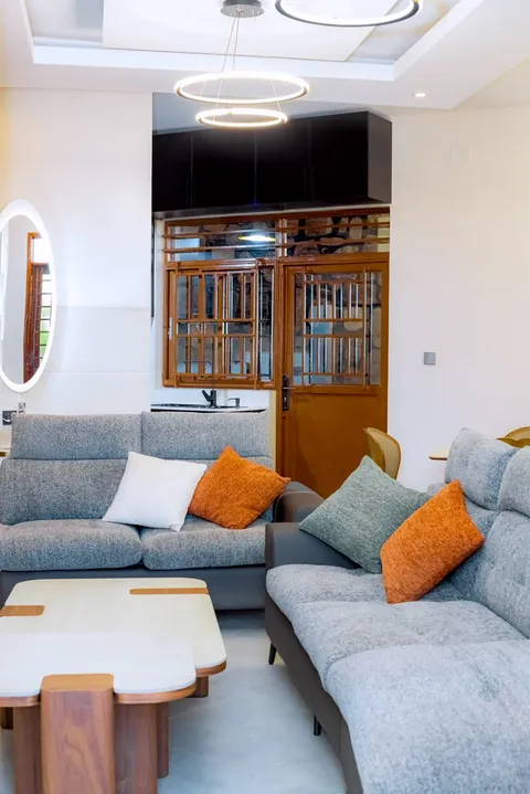 Gray sectional seating with accent cushions, coffee tables and a dining area behind