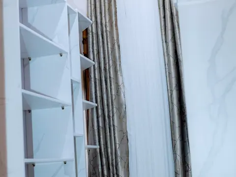 White open shelves and wardrobe doors beside full-length curtains