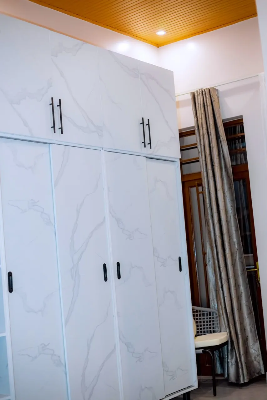 Full-height white wardrobes with dark handles beneath a wood-toned ceiling