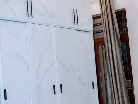 Full-height white wardrobes with dark handles beneath a wood-toned ceiling